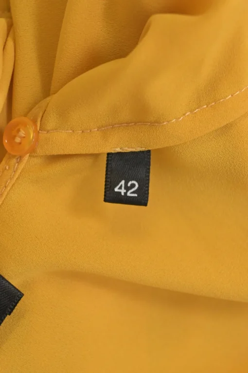 Mustard yellow polyester Bertha bib open-back ruffle blouse with draped waistband and sleeve cuffs
