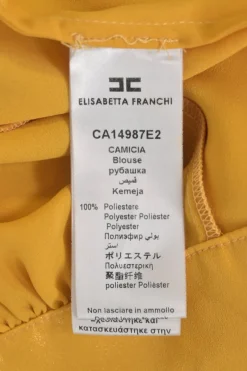 Mustard yellow polyester Bertha bib open-back ruffle blouse with draped waistband and sleeve cuffs