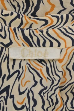 Orange abstract swirl print plunge neck tie-front logo tunic with dagger collar and bishop sleeves