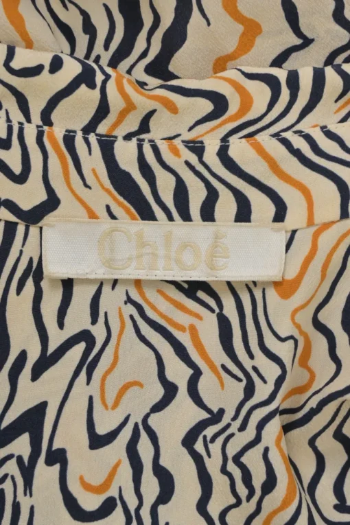 Orange abstract swirl print plunge neck tie-front logo tunic with dagger collar and bishop sleeves