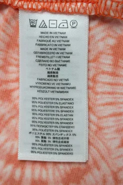 Orange tie dye patterned sleeveless drape top adorned with golden logo debossed hardware on one strap.