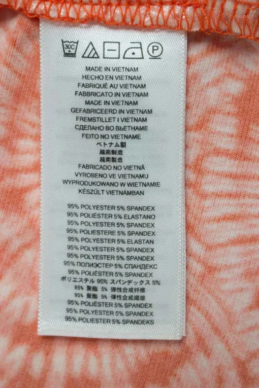 Orange tie dye patterned sleeveless drape top adorned with golden logo debossed hardware on one strap.