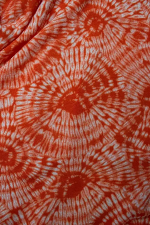 Orange tie dye patterned sleeveless drape top adorned with golden logo debossed hardware on one strap.