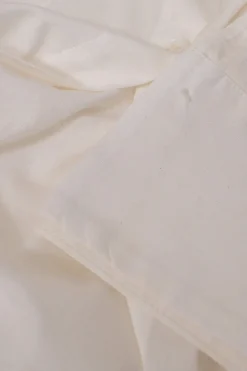 White frill-trimmed polyester cold-shoulder swing-style shirt with exposed button placket and high-low hem