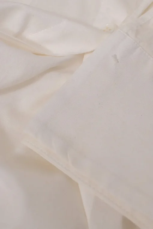 White frill-trimmed polyester cold-shoulder swing-style shirt with exposed button placket and high-low hem