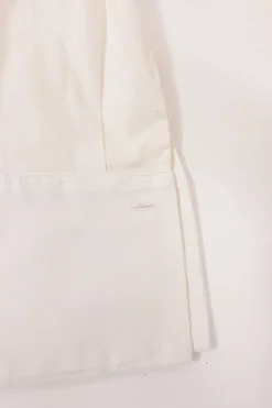 White frill-trimmed polyester cold-shoulder swing-style shirt with exposed button placket and high-low hem
