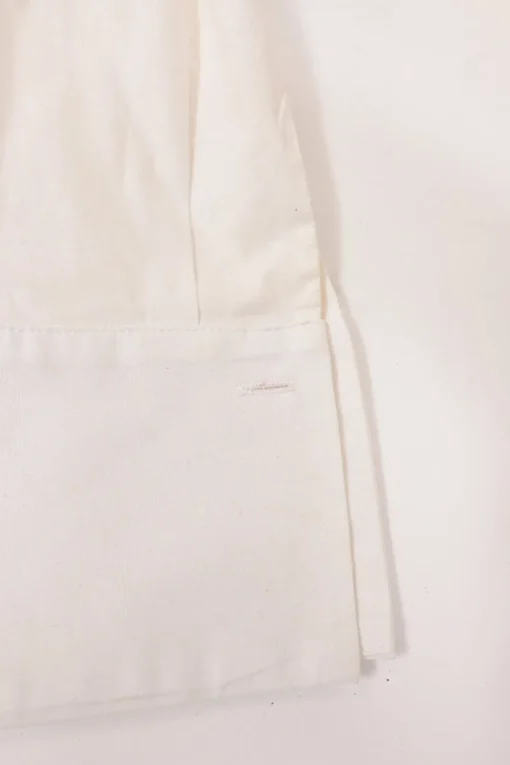 White frill-trimmed polyester cold-shoulder swing-style shirt with exposed button placket and high-low hem